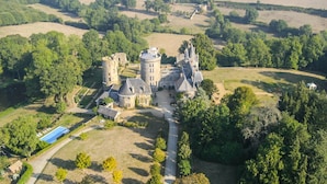 A large, historic castle with multiple towers and a well-maintained lawn.