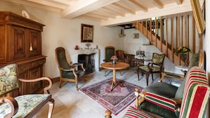 Un interior tradicional con chimenea, muebles de madera, una alfombra estampada y una escalera.