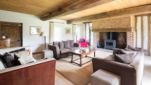 Un salon chaleureux avec une cheminée, des poutres en bois et des sièges confortables.