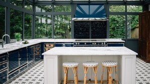 A modern kitchen with a large island, built-in cabinets, and a glass-enclosed structure.