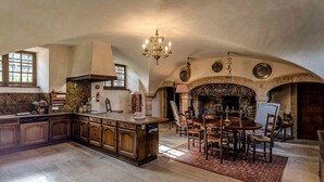 A spacious kitchen with a large island, wooden cabinets, and a dining area with a fireplace. - Chateau Les Douves - Eight Bedroom Castle, Sleeps 14 (Fontenay-sur-Mer)