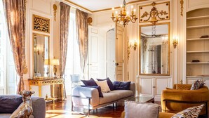 A luxurious living room with a sofa, armchairs, a coffee table, and a chandelier.