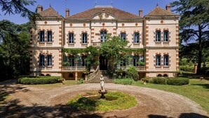 Un grand bâtiment aux proportions harmonieuses, doté d’un escalier central et entouré de jardins bien entretenus ainsi que d’une fontaine.