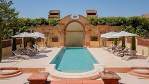Un espace piscine doté d’une piscine à l’eau cristalline, de chaises longues et de parasols.