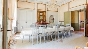 Une salle à manger élégante, avec une longue table dressée pour accueillir de nombreux convives, un lustre et un miroir au-dessus de la table.