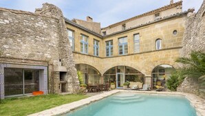 A courtyard with a swimming pool, stone buildings, and arched windows.