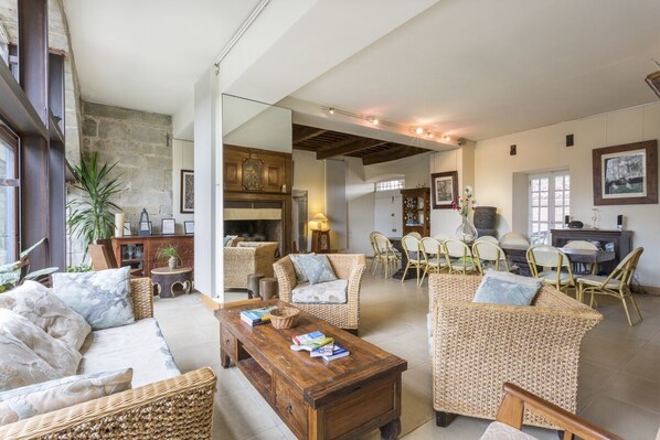 A spacious living area with wicker furniture, a wooden coffee table, and a dining area with chairs and a table.