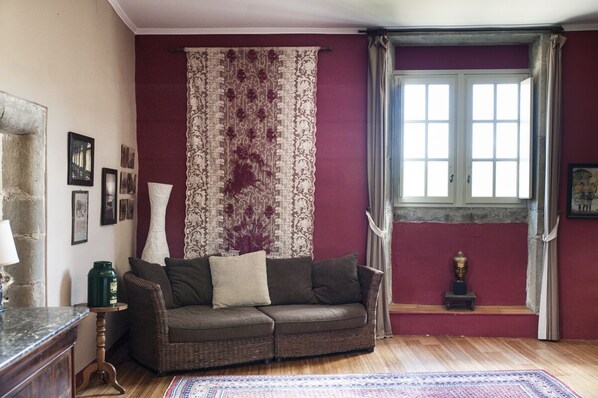 A living room with a brown sofa, a patterned curtain, and a window with curtains.