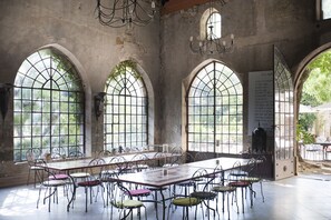A large room with a long table and chairs, arched windows, and a chandelier.
