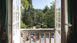 Ein offenes Fenster mit Blick auf einen Garten mit Bäumen und Gartenmöbeln.
