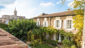 Une cour intérieure avec un bâtiment doté de volets blancs et d’un toit recouvert de tuiles.