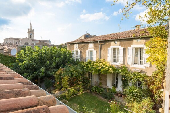 A courtyard with a building featuring white shutters and a tiled roof. - L'Oustal Des Fleurs - Four Bedroom Villa, Sleeps 8 (Olonzac)