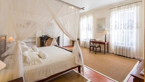 Une chambre à coucher avec un lit à baldaquin, un bureau et une chaise.