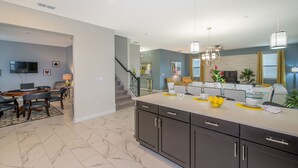 A modern kitchen with dark cabinetry, a marble floor, and a dining area with a round table and chairs. - Luxury Villa Storey Lake, 15min→Disney, private pool + hot tub + No Extra Fees (Kissimmee)
