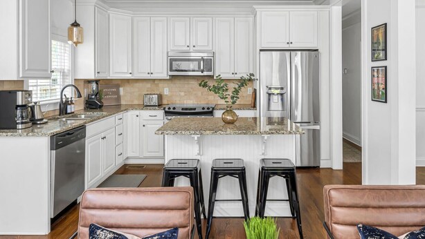 A modern kitchen with white cabinetry, stainless steel appliances, and a granite countertop.