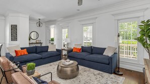 A spacious living room with two dark blue sofas, a coffee table, and a ceiling fan.