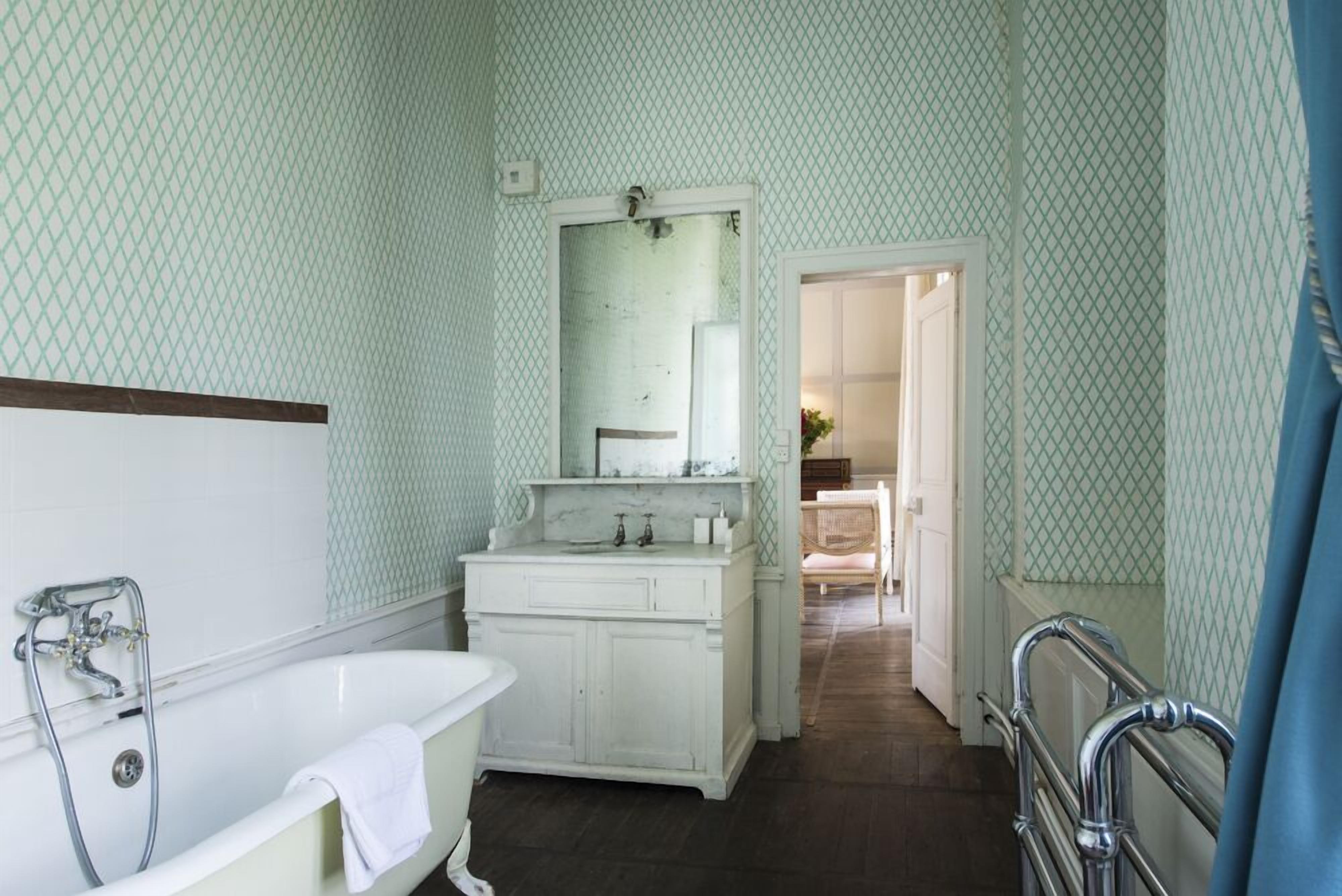 Une salle de bain avec une baignoire blanche, un meuble-lavabo avec un miroir et un espace douche.