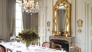 A dining room with a chandelier, a large ornate mirror, and a fireplace.