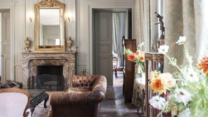 A room with a fireplace, leather armchair, and a large mirror.