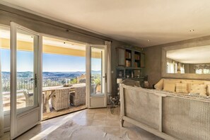 A room with a balcony, wicker furniture, a bookshelf, and a large mirror.