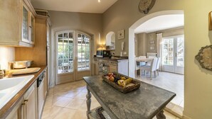 Una cocina con zona de comedor, una cesta de fruta sobre la mesa y un reloj en la pared.