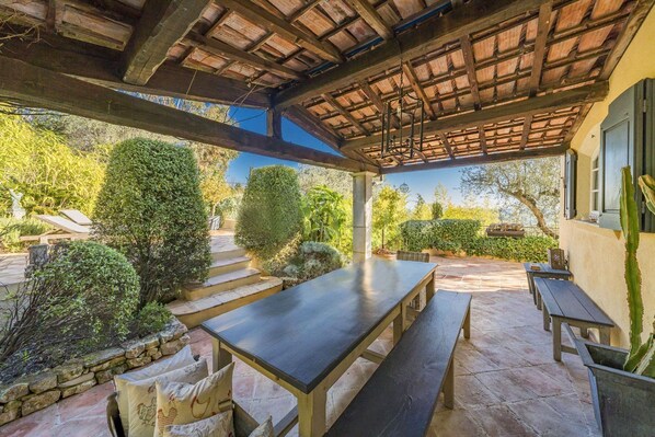 An outdoor patio with stone flooring, wooden benches, and a table.