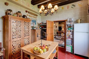 A kitchen with wooden cabinets, a fruit bowl on the counter, and a chandelier.