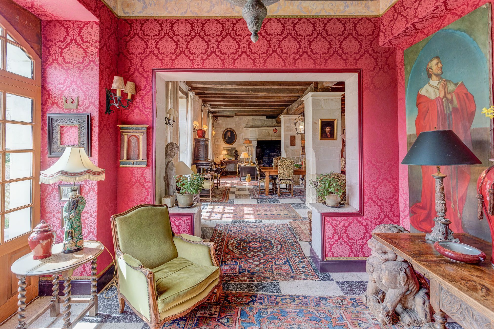 Um quarto com uma poltrona verde, um tapete estampado e uma pintura na parede.