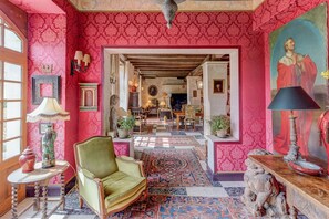 A room with a green armchair, a patterned rug, and a painting on the wall.