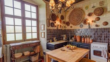 A traditional kitchen with a large window, a wooden table, and various kitchen utensils.