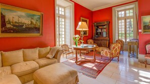 Une pièce avec un mur rouge, un canapé beige, une table basse en bois et un tapis à motifs.