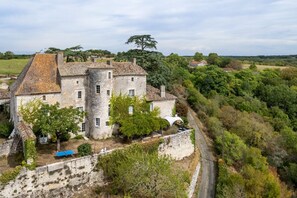 Un bâtiment en pierre doté d’une cour intérieure, entouré d’arbres et d’un mur de pierre.