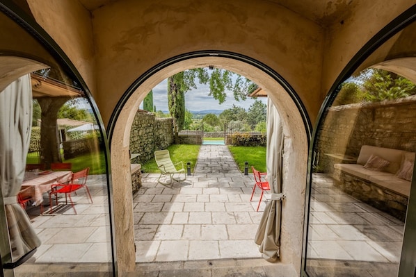 An outdoor patio with a stone pathway, red chairs, and a view of a garden and mountains.