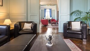 Amplia sala de estar con sofás de cuero, una mesa de centro y un comedor al fondo.