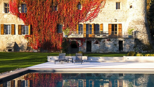 Un bâtiment en pierre doté d’une piscine et d’un espace extérieur aménagé pour s’asseoir.