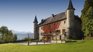 Un château doté de deux tours, d’une façade en pierre et offrant une vue sur les montagnes.
