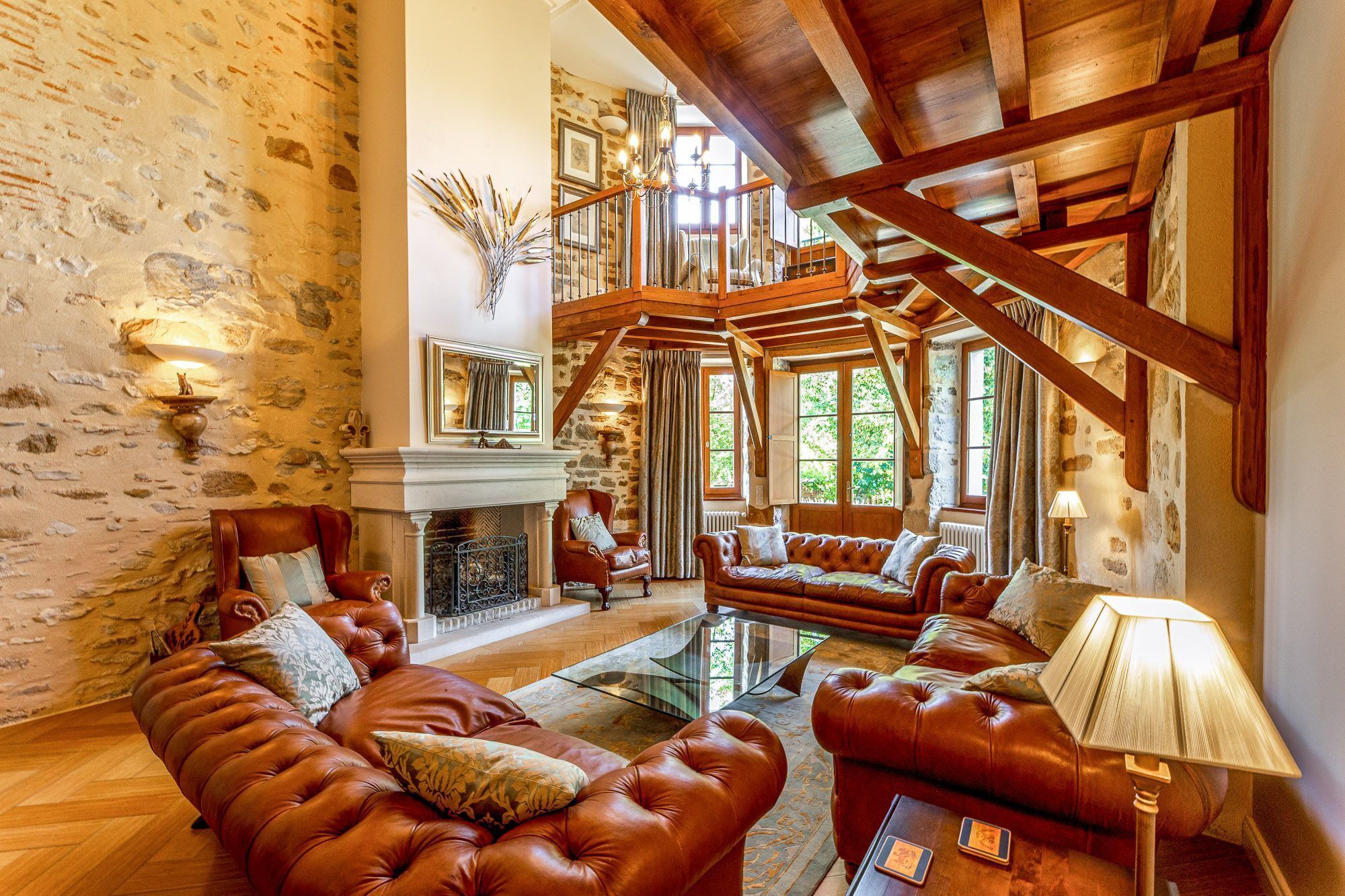A spacious living area with a fireplace, leather sofas, and a staircase leading to an upper level.
