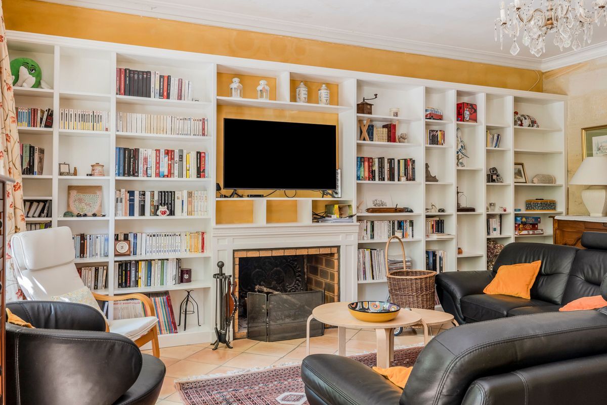 Un salon doté d’une cheminée, de bibliothèques, d’un téléviseur et de meubles en cuir.