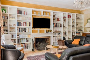 Un salon doté d’une cheminée, de bibliothèques, d’un téléviseur et de meubles en cuir.