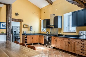 Een keuken met houten kastjes, een fornuis en een groot raam.