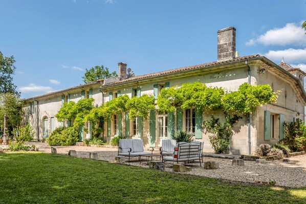 A two-story building with a garden patio, outdoor seating, and a clear sky.