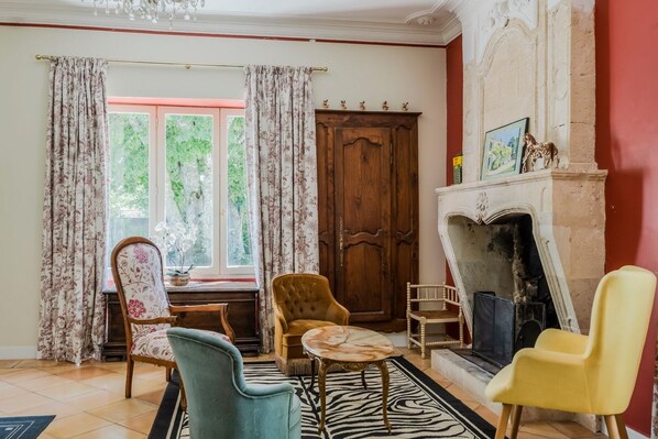 A room with a fireplace, a wooden door, and a window with curtains.