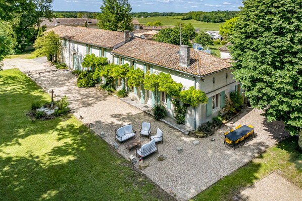 Un bâtiment à deux étages doté d’une terrasse en gravier et d’un espace extérieur aménagé pour s’asseoir.