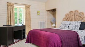 Une chambre à coucher avec un lit, un bureau, un radiateur et une fenêtre avec des rideaux.