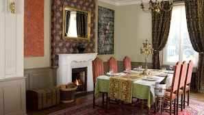 A dining room with a fireplace, a chandelier, and a view of the outdoors.