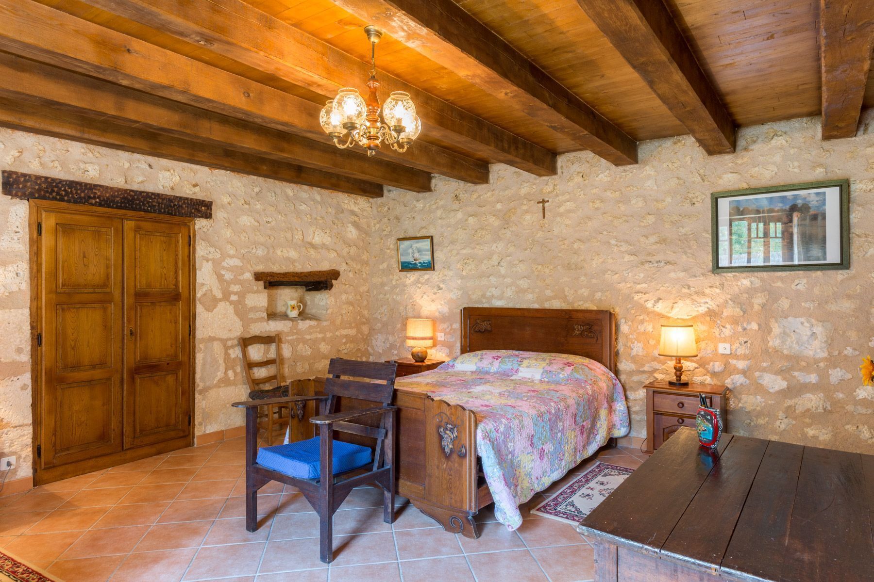 Une chambre rustique avec un lit en bois, un bureau et une chaise, un mur en pierre et un plafond en bois.