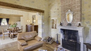 Una sala de estar acogedora con chimenea, un comedor con mesa y sillas de madera, y una cocina al fondo.