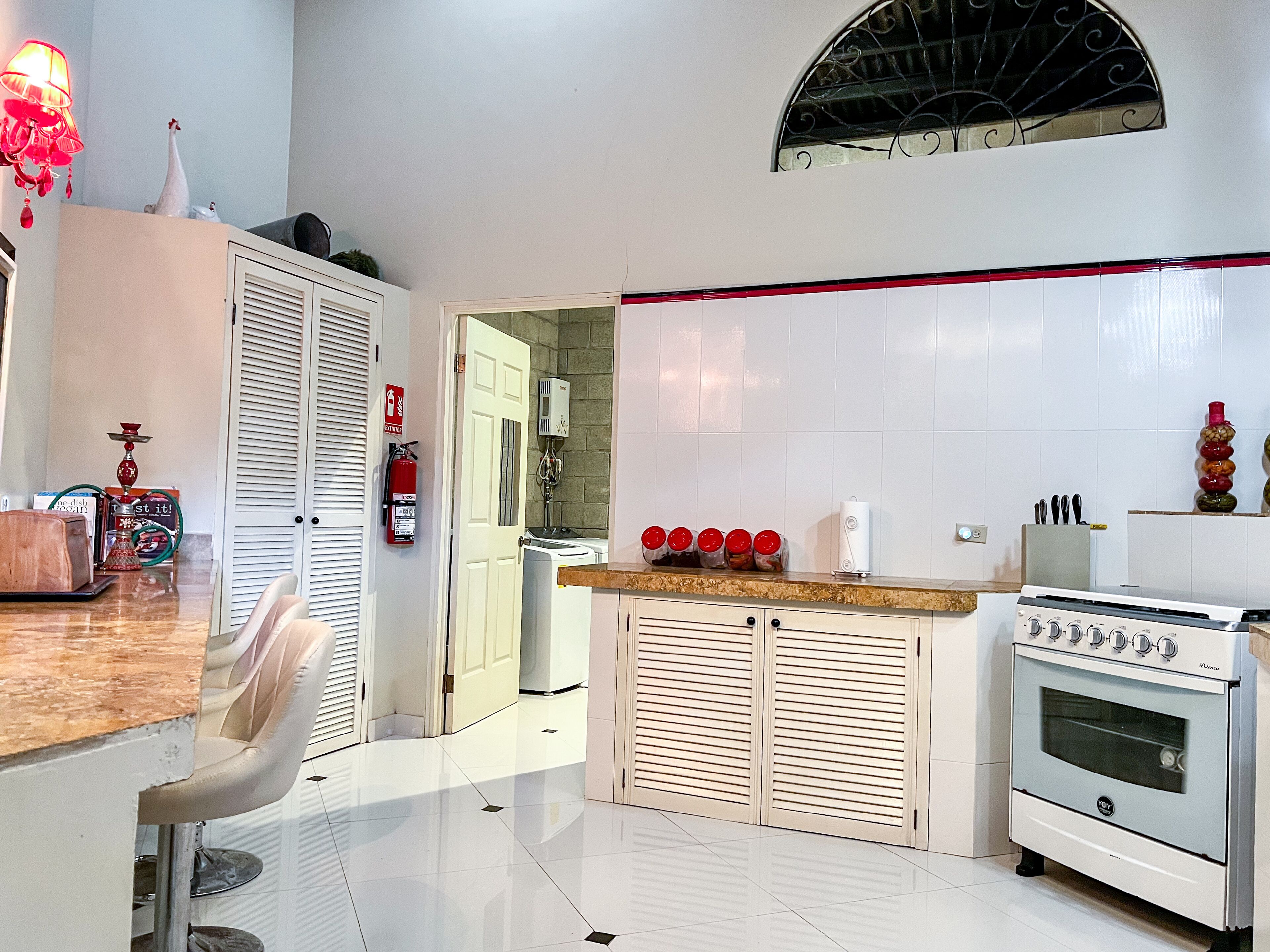 A modern kitchen with white cabinets, a built-in oven, and a dining area with a table and chairs.