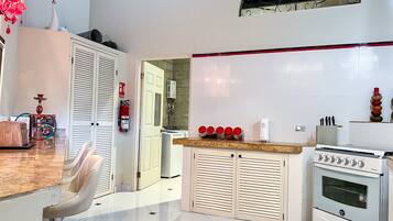 A modern kitchen with white cabinets, a built-in oven, and a dining area with a table and chairs.