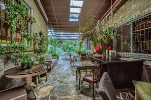 A cozy indoor garden with stone flooring, wooden furniture, and various potted plants. - Casa Madre Tierra (Los Llanitos)
